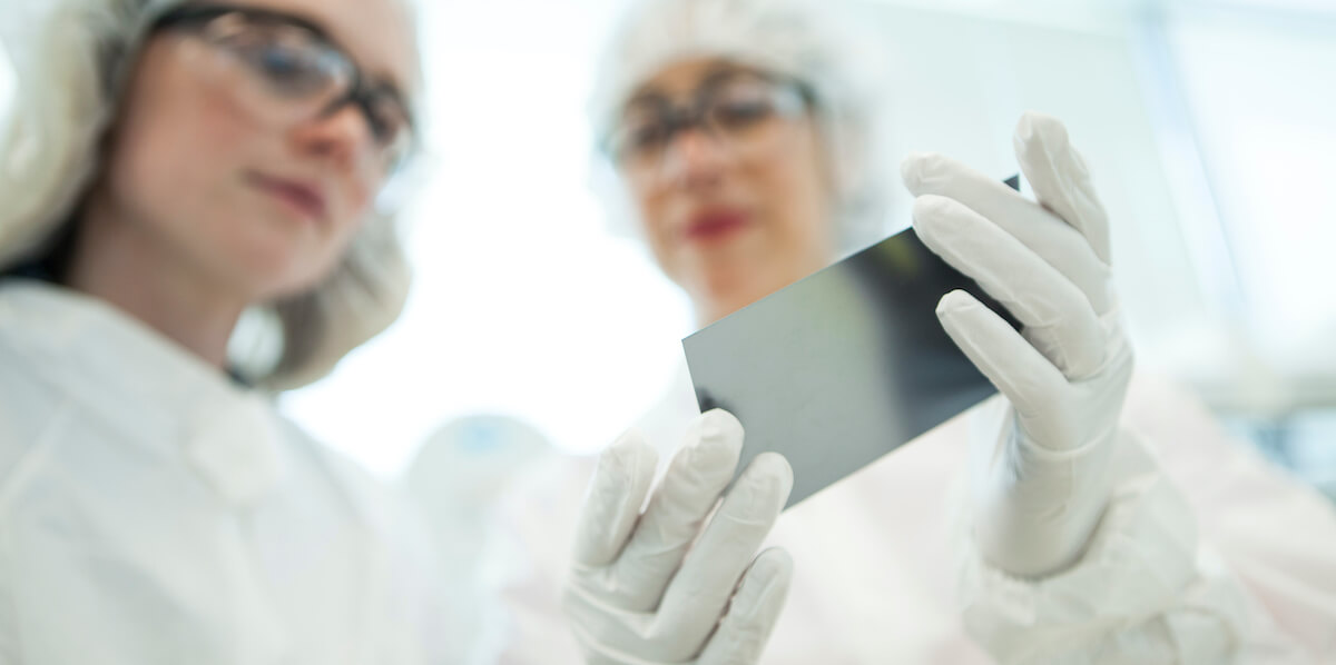 Twist scientists examining a silicon chip used to synthesize oligonucleotides for many applications, including custom DNA target enrichment panels.