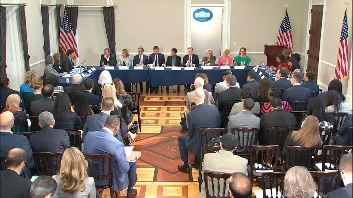 Picture of room full of chairs in front of panel of white house speakers during listening session